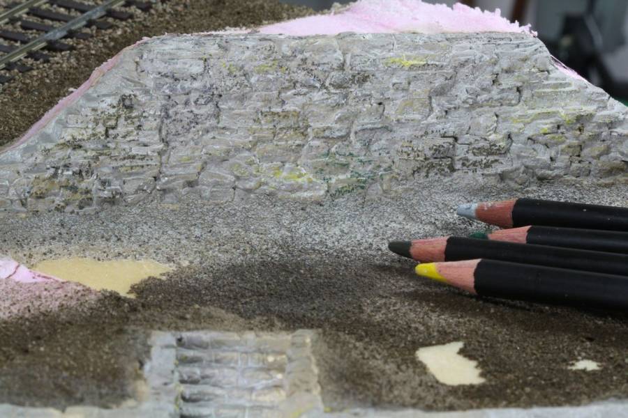 Farbstifte und dünne Lasuren setzen erste Nuancen auf einzelnen Steinen.