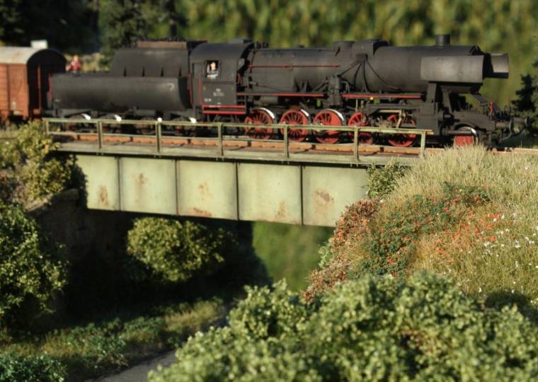 Dampflok auf der verwitterten Stahlbrücke